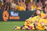 The Matildas pile on to celebrate a goal.