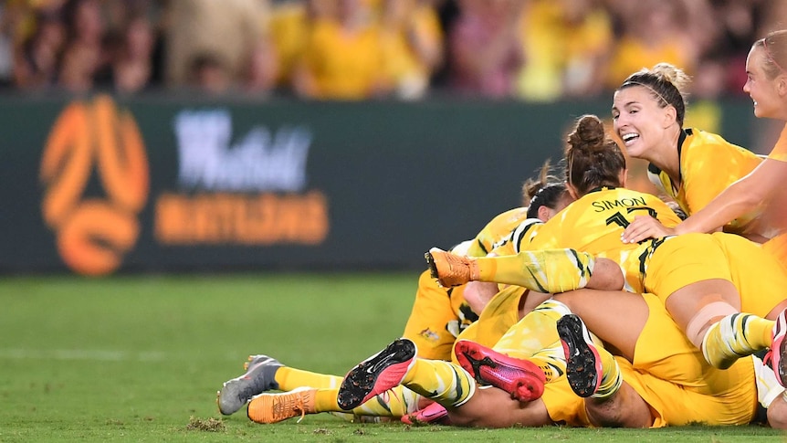 The Matildas pile on to celebrate a goal.