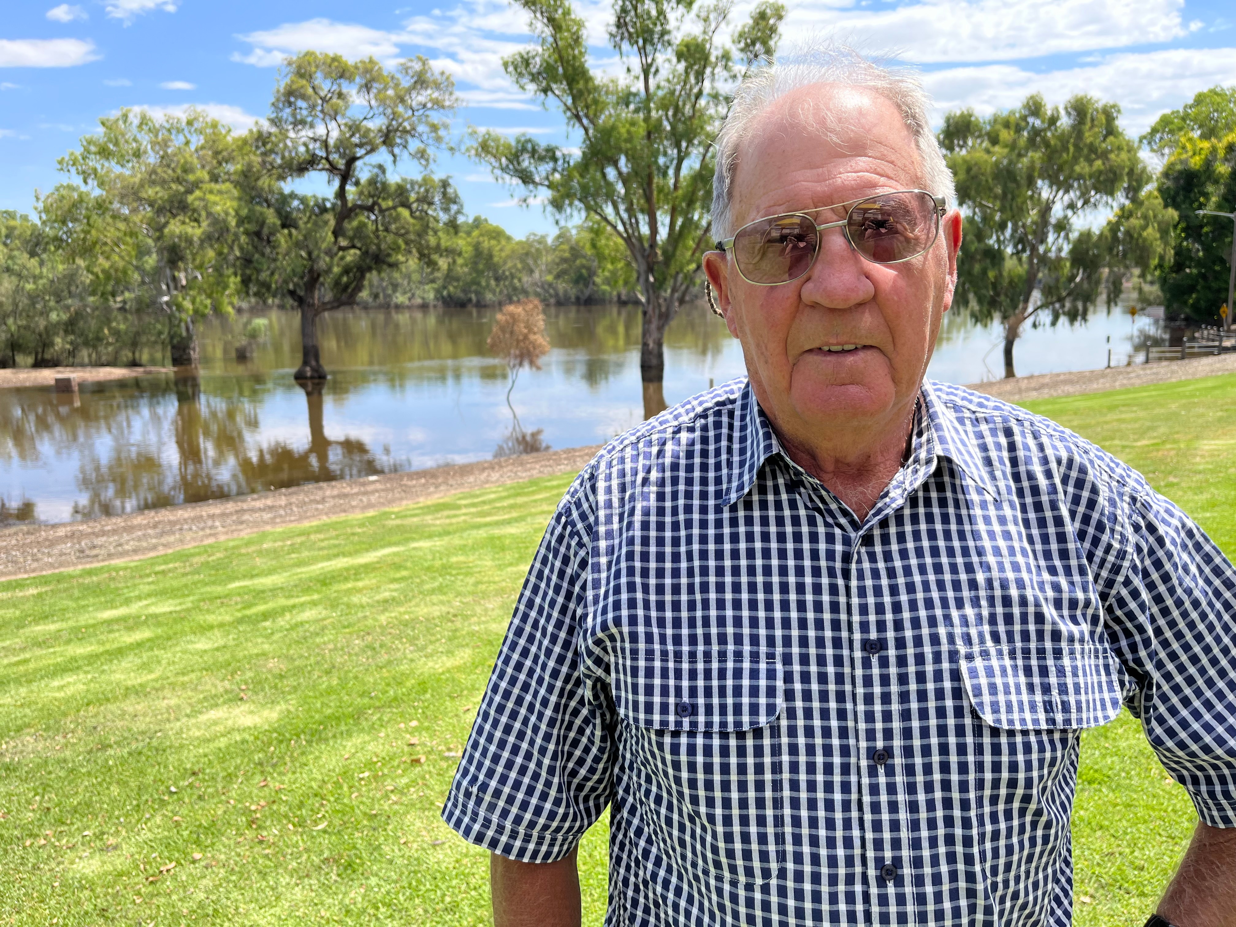 Howard Jones stands on lawn with flood water in the background