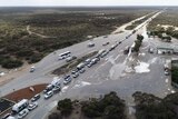 An aerial shot of a long queue of cars on a remote highway checkpoint.