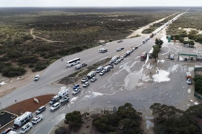 An aerial shot of a long queue of cars on a remote highway checkpoint.