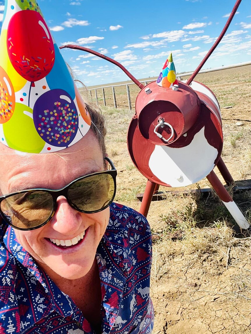woman wearing birthday hat takes selfie with metal mailbox cow also wearing party hat