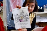 Two Hazara children (girls) hold up poster in classroom