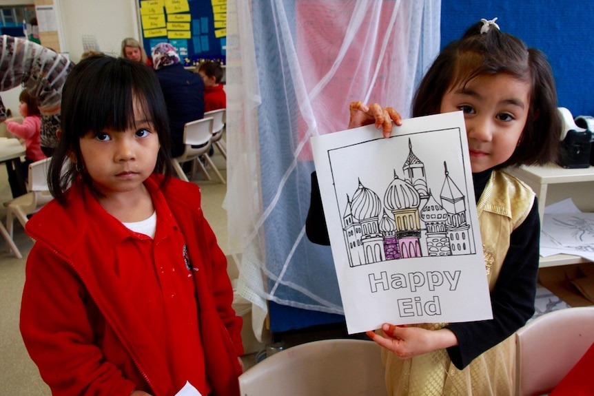 Two Hazara children (girls) hold up poster in classroom