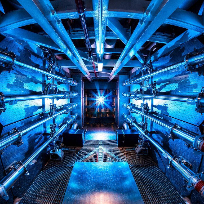 A blue-lit laboratory with pipes running along the walls