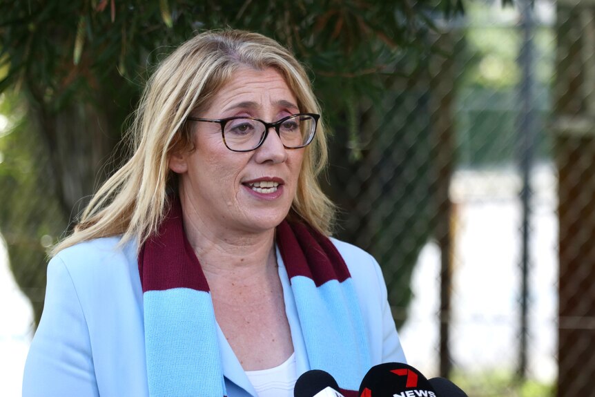 WA Deputy Premier Rita Saffioti speaking at a media conference outside wearing a blue jacket and West Ham scarf.