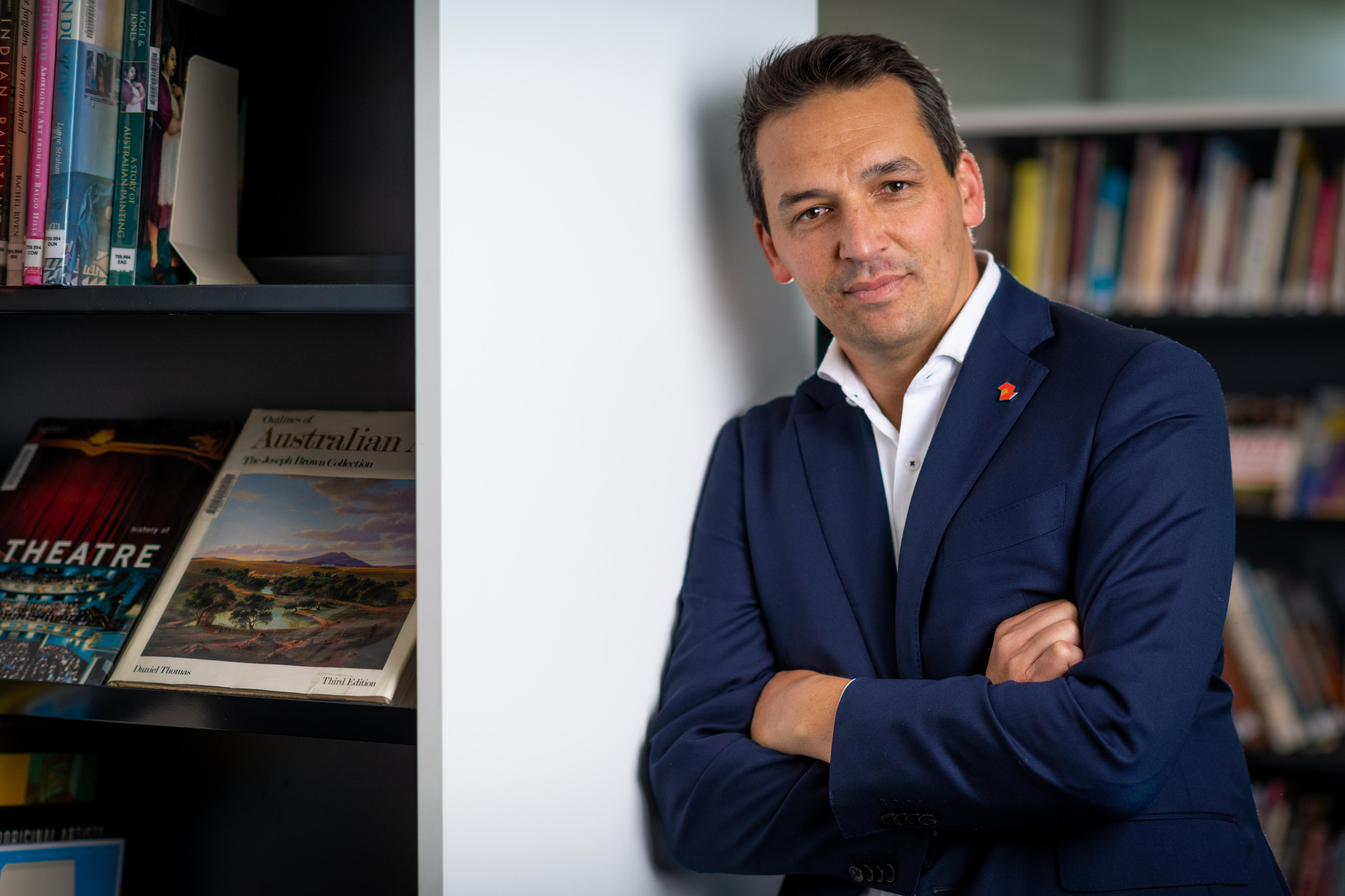 Blair Boyer leaning against a bookcase, his expression neutral