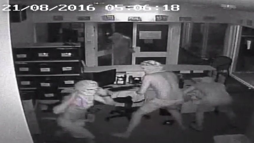CCTV still of the four hooded , shirtless young makes in the office
