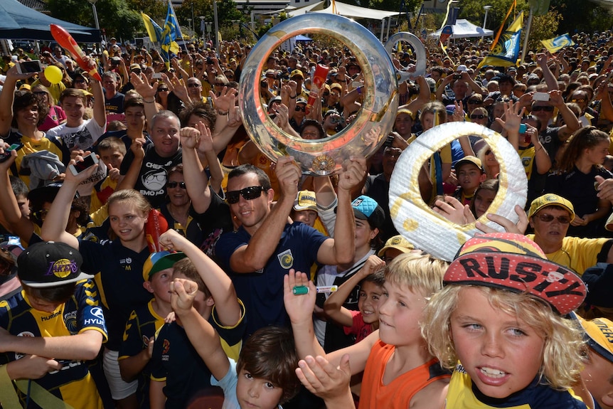 Central Coast Mariners captain John Hutchinson holds up the A-League champions trophy.