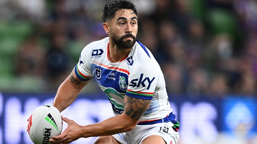Shaun Johnson of the Warriors holding the football during an NRL match, preparing to pass to his left