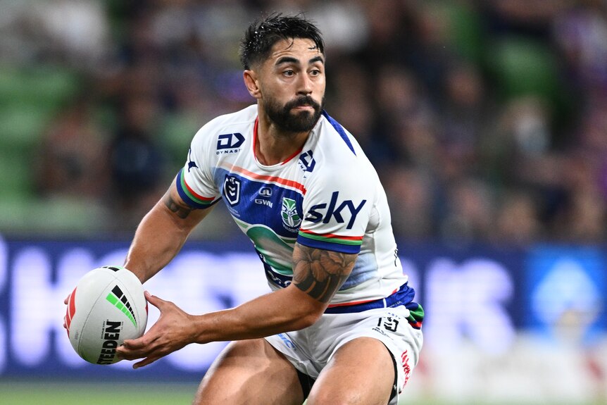 Shaun Johnson of the Warriors holding the football during an NRL match, preparing to pass to his left