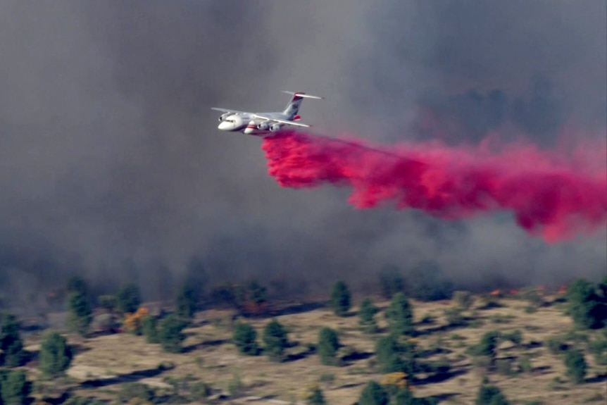 An aerial appliance drops pink retardant on a fire