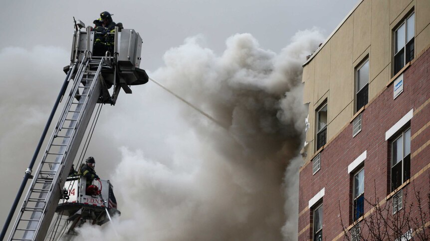 Firefighters try to extinguish a fire at the site of the building collapse at Harlem