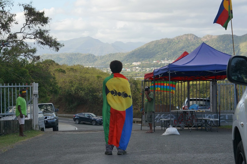 Man draped in Kanaky Flag overlooking hills in New Caledonia