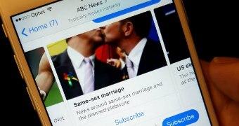 A close-up photo of a person holding a phone displaying a message from ABC News on Facebook Messenger.