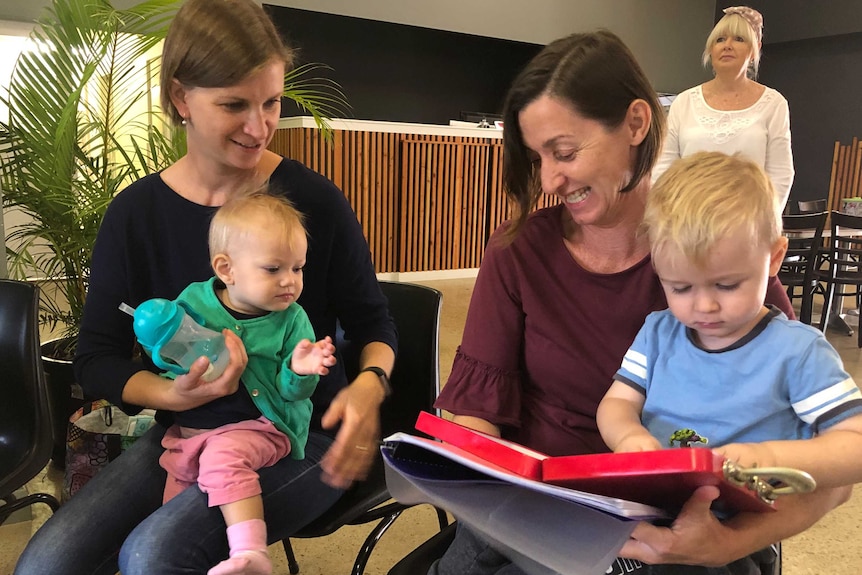 Two mums sitting with children on their laps in a choir.