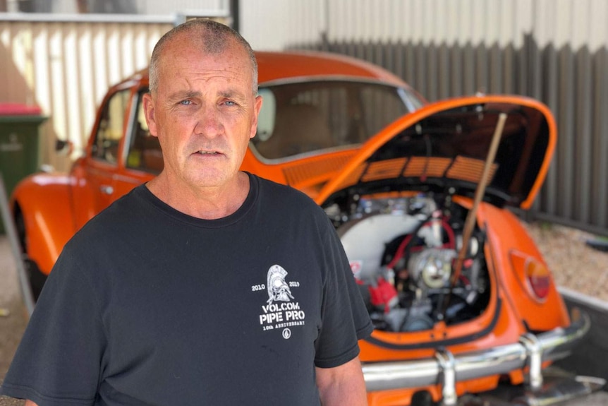 Mark Stephens stands in front of his restored orange VM Beetle car.