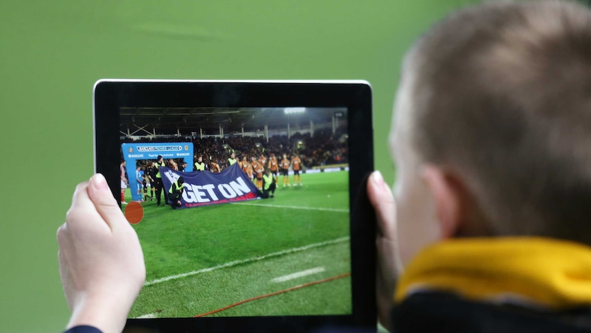 Fan poses with a tablet as teams line up before a Premier League match between Hull and Sunderland.