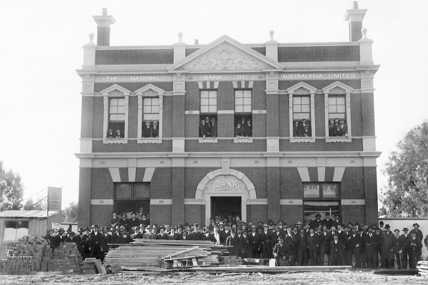 a black and white photo of a historic building in Dimboola with men in top hats and coats.