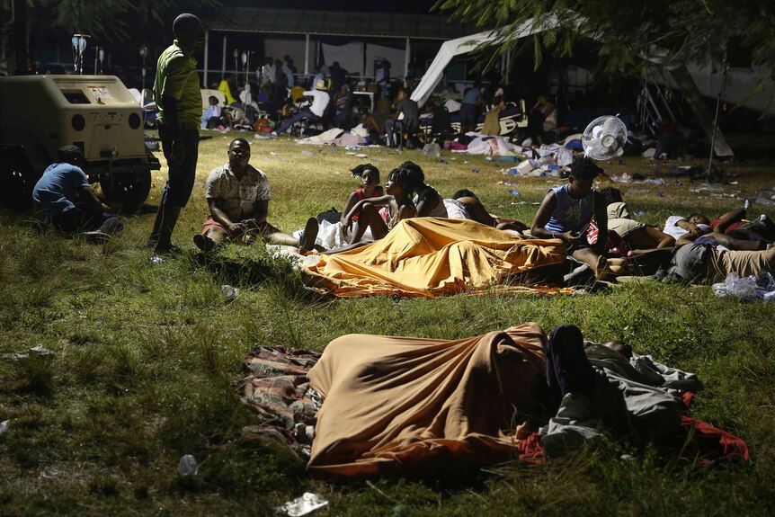 People camp in a park at night in Haiti.