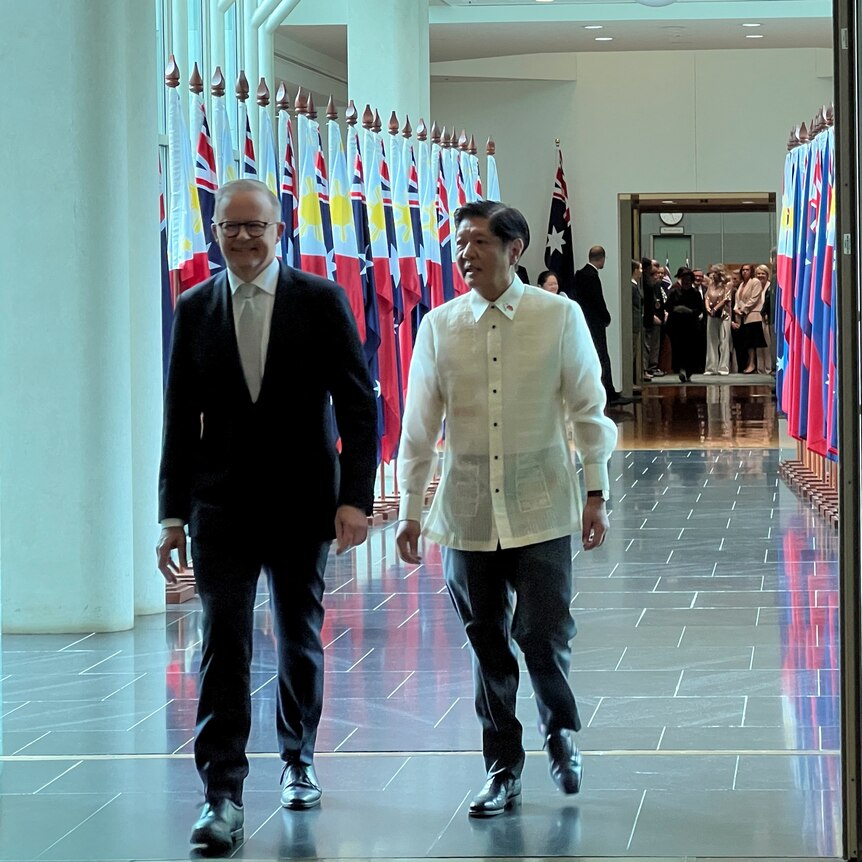 Anthony Albanese walks past flags with Philippine President Ferdinand Marcos Jr at Parliament House as a crowd watches.