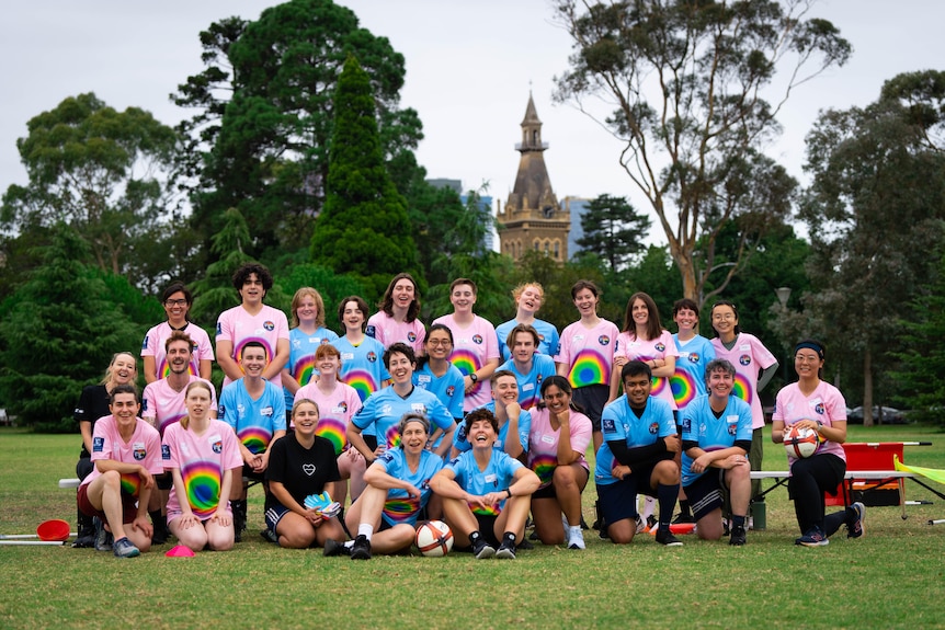 A group shot of more than 25 people wearing blue and pink t-shirts, posing for the camera.
