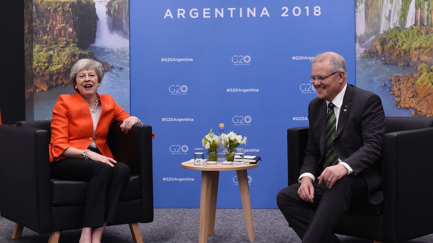 UK Prime Minister Theresa May and Scott Morrison sit on armchairs and laugh