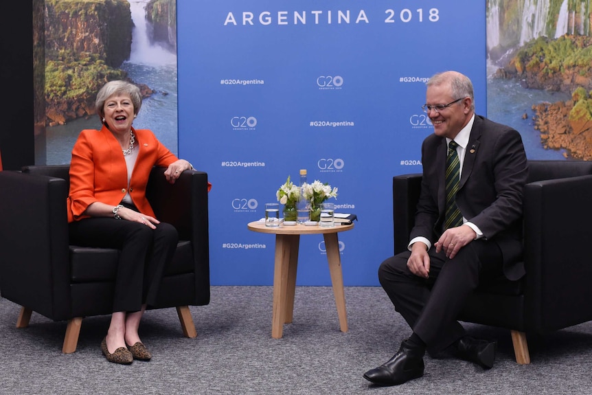 UK Prime Minister Theresa May and Scott Morrison sit on armchairs and laugh