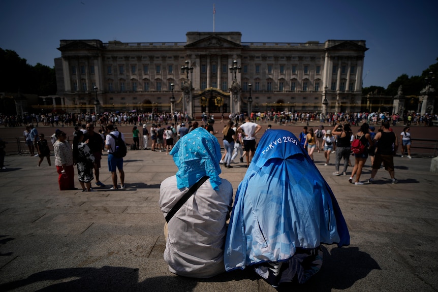 People sit covering their heads from the sun in London