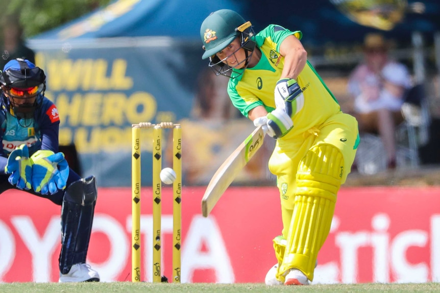 A female Australian cricketer hits to the off side as the Sri Lanka wicketkeeper looks on during the ODI.