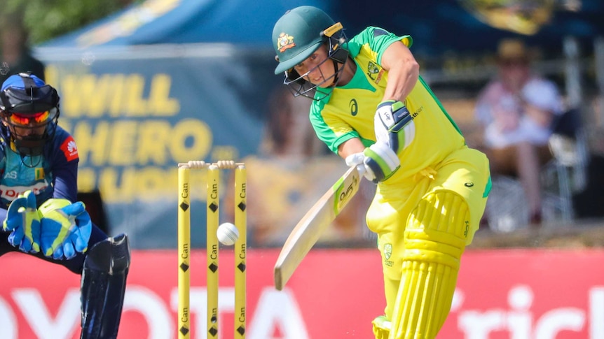 A female Australian cricketer hits to the off side as the Sri Lanka wicketkeeper looks on during the ODI.