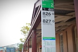 A close up of a bus sign, an old railway building in background