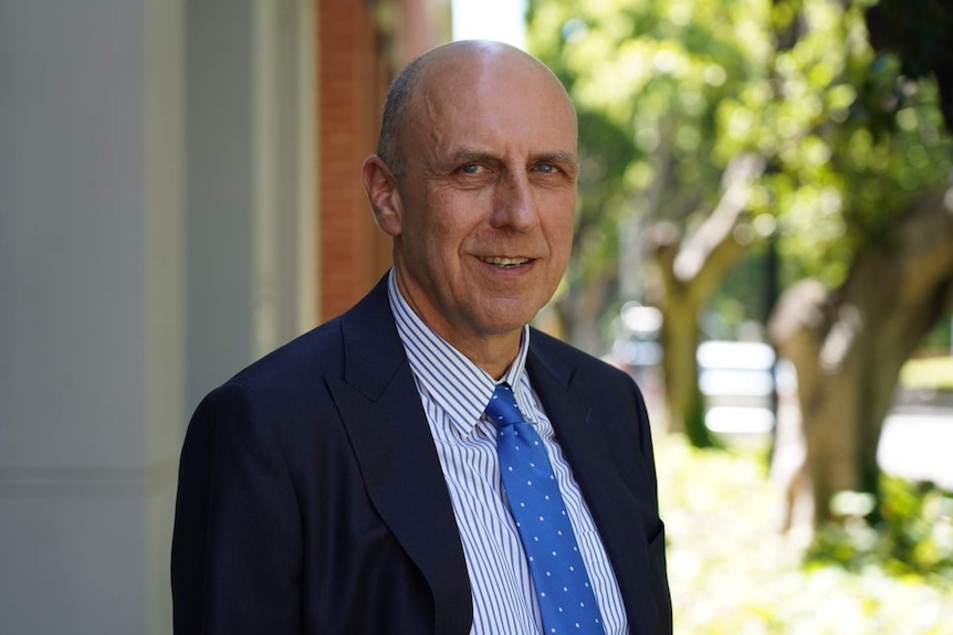 A man in a blue tie poses for a photo