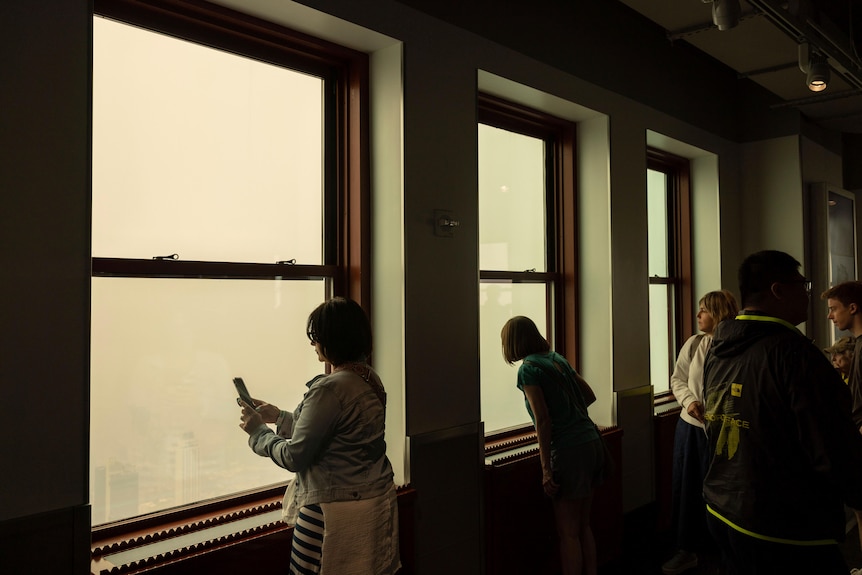 People standing next to window with yellow haze outside. 