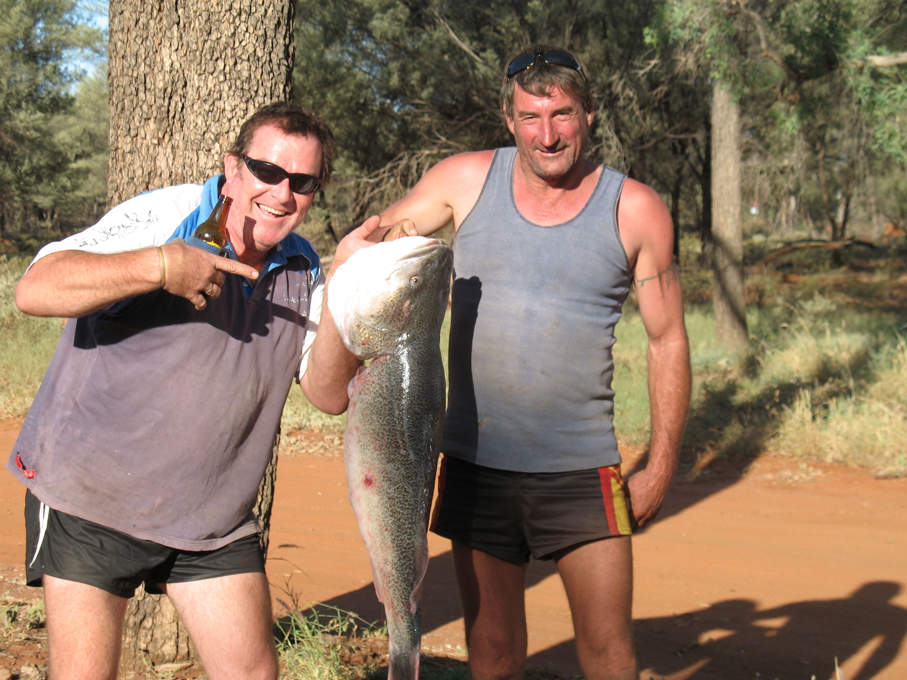 Two men holding a large Murray Cod on the banks of the Ward River near Charleville, Queensland