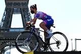 Amanda Spratt poses for a picture on her bike, wearing a mask with the Eiffel Tour in the background