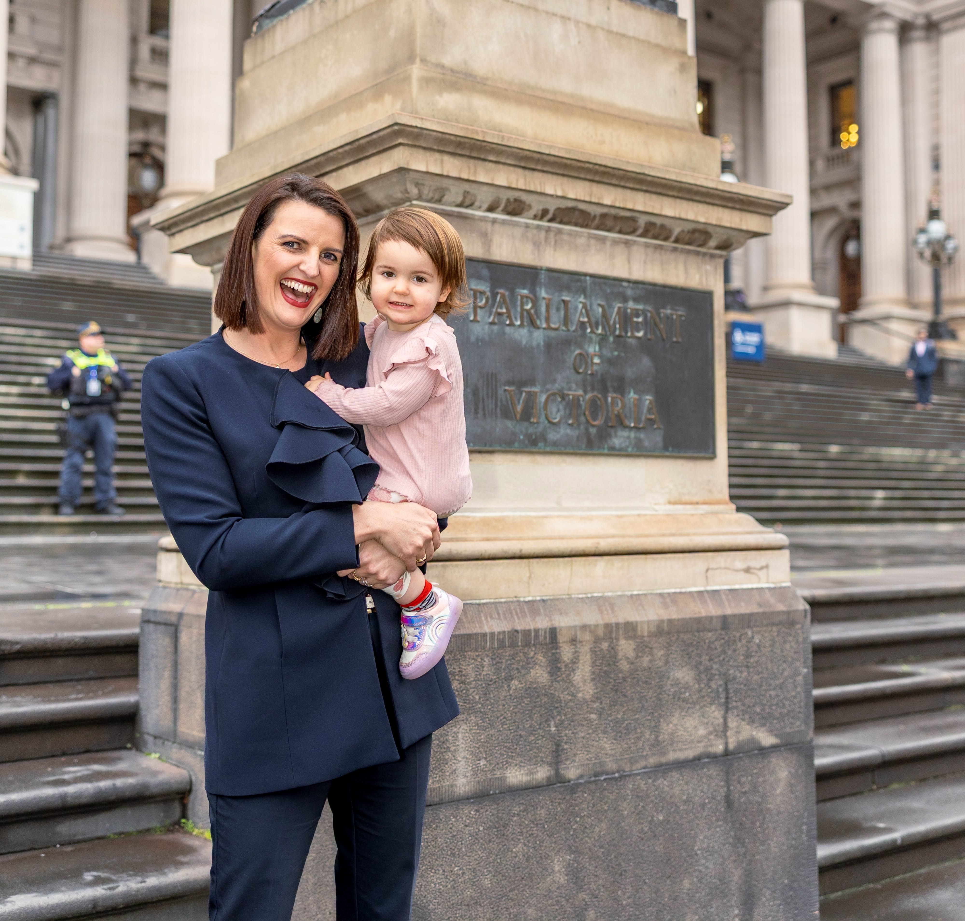Annabelle Cleeland holds a little girl in her arms outside parliament house steps.
