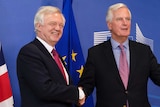 Michel Barnier and David Davis shake hands in front of British and EU flags.