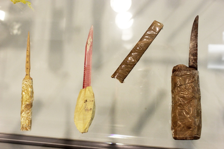 Home made knives with handles in a glass display cabinet.