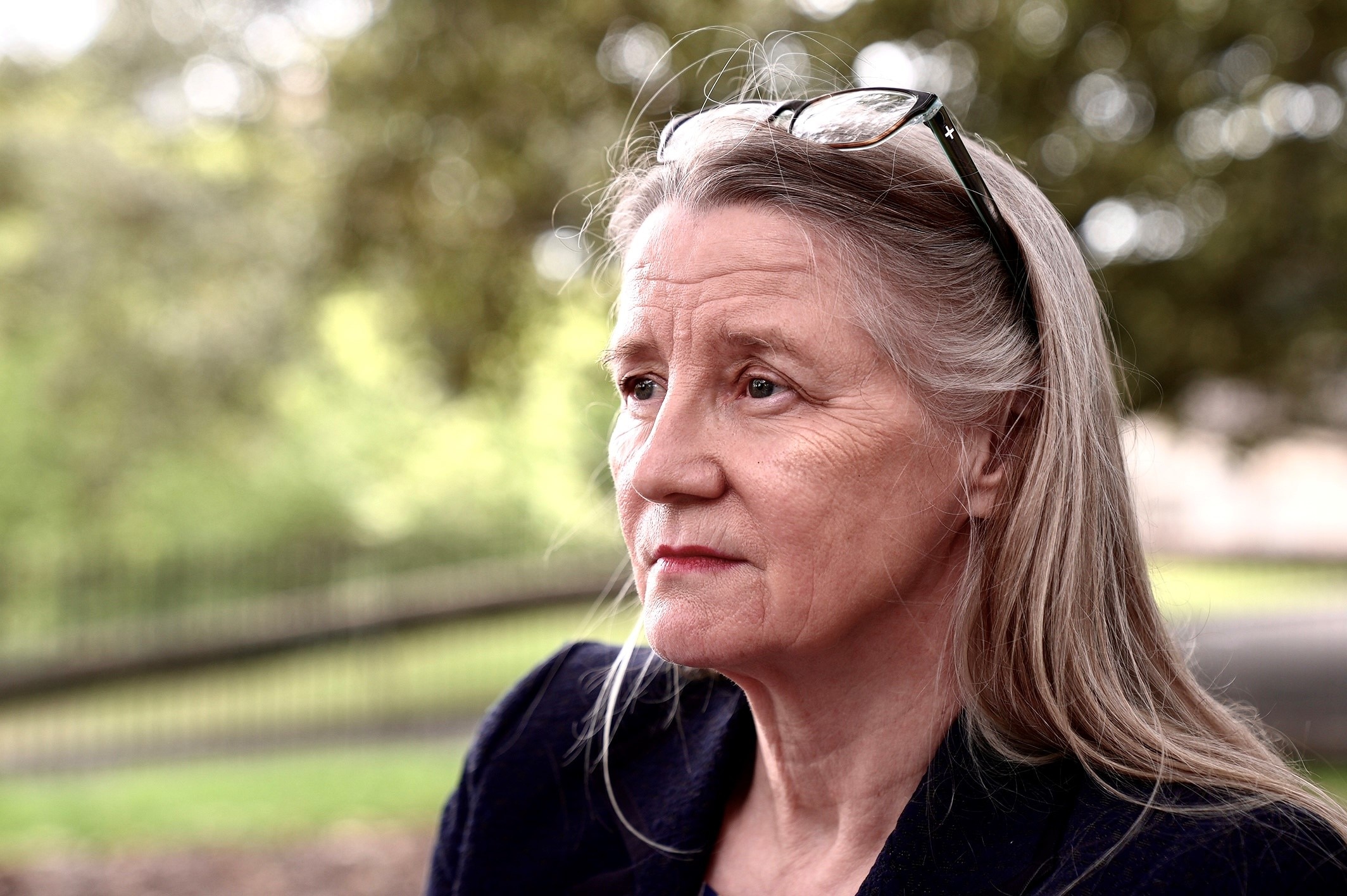 Karen Payne in Sydney sitting at a park bench looking into the distance. 