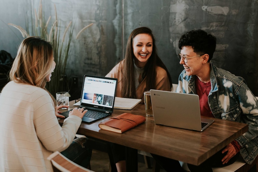 Photo of a study group smiling together at a desk. Groups like this a great way for students at university to share tips.