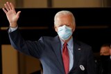 Joe Biden, wearing a mask waves to people.