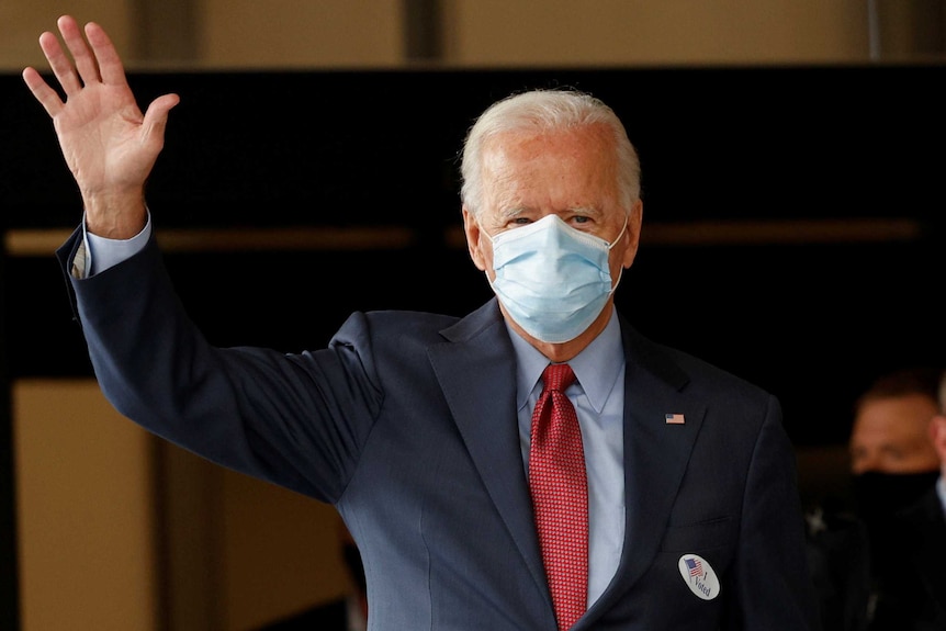 Joe Biden, wearing a mask waves to people.