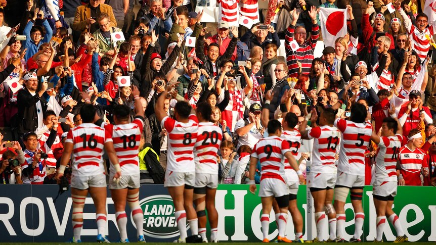 Japan players celebrate in front of fans after beating Samoa