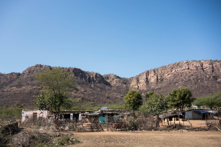 Shack houses under a rock cliff in a dry landscape