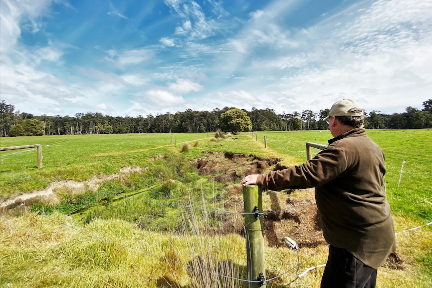 Farmer Malcolm stands and looks over the severely eroded drain he dug 40 years ago across his paddock.