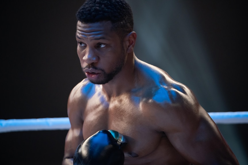 Jonathan Majors as Damian Anderson with boxing gloves on in a ring, shirt off facing an unseen opponent