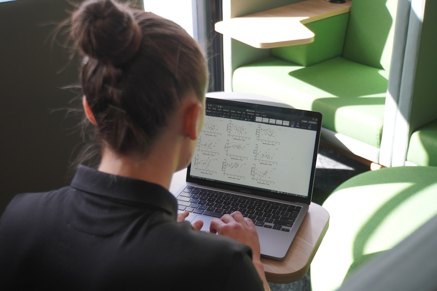 Mikayla Lyons sits in a booth studying data on a computer