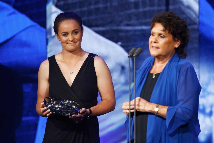 Ash Barty watches Evonne Goolagong Cawley speaking into a microphone after receiving a Tennis Australia award.