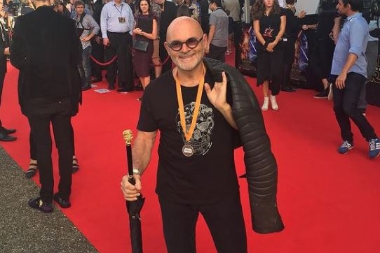 A man wearing glasses walks on a red carpet